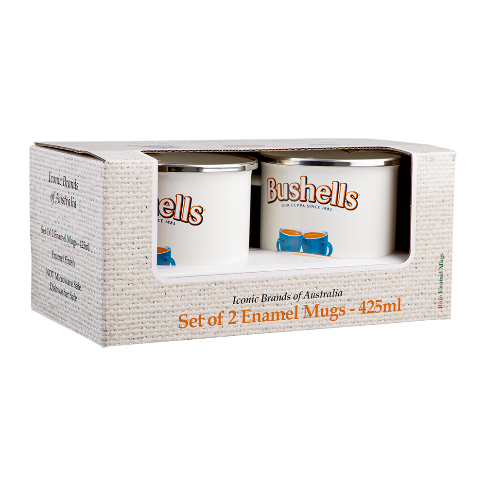 A boxed set of two white enamel mugs with silver metal rims, displayed in a textured white cardboard package. The mugs are branded 'Bushells' with blue cup illustrations.