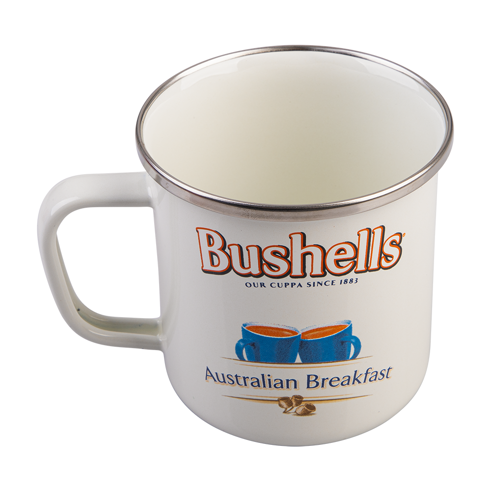 A white enamel camping mug with a silver metal rim, featuring the Bushells brand logo and 'Australian Breakfast' text printed on the front.
