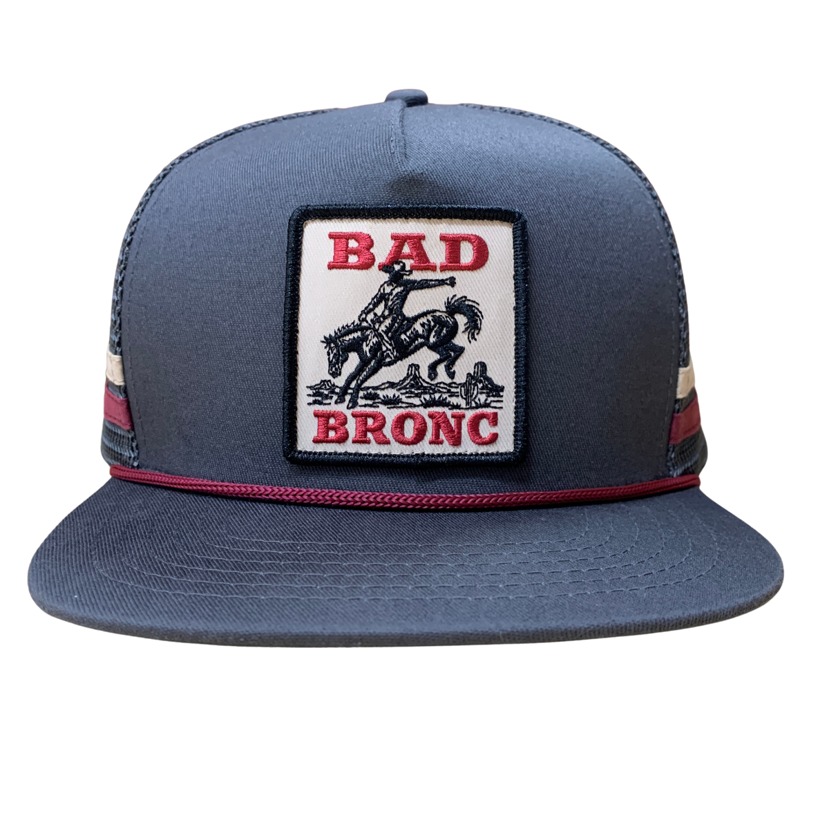 A dark slate blue snapback cap featuring a rectangular front patch with the words 'BAD BRONC' in red and a black cowboy on a bucking horse graphic on a white background. The cap has red and white striped mesh side panels and a red accent line under the brim.