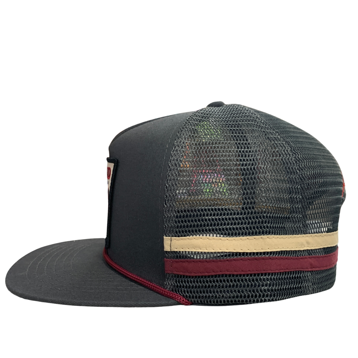 A black trucker-style cap with a black mesh back, featuring a beige horizontal stripe and a burgundy stripe on the back band, with a small embroidered logo on the side.