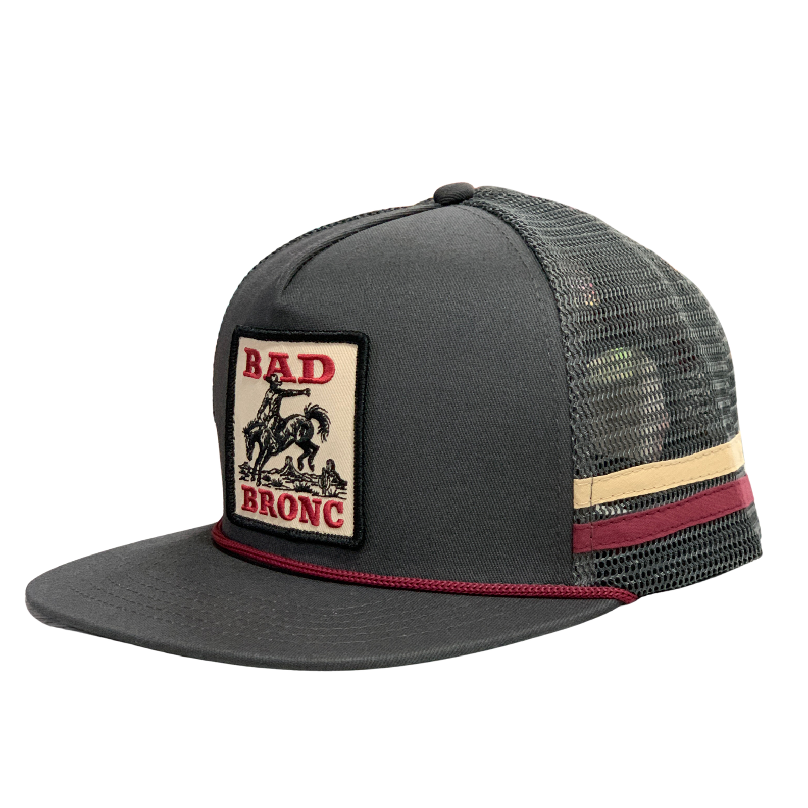 A dark gray trucker hat with a beige and red 'Bad Bronc' patch on the front, featuring a camouflage mesh back and a beige and red stripe detail on the side.