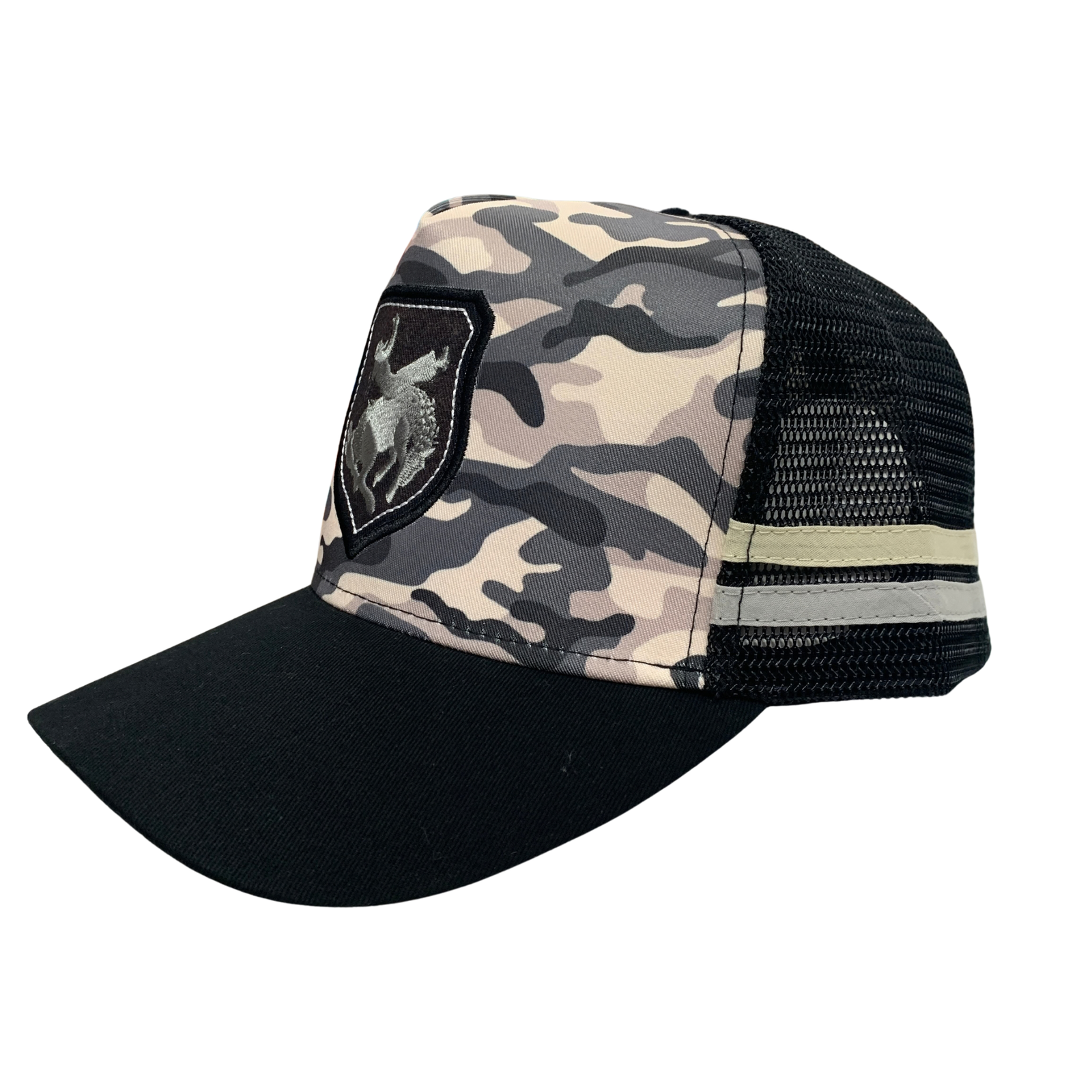 A trucker-style baseball cap with a black curved brim, black mesh back, and a front panel featuring a beige, gray, and black camouflage pattern. A black shield patch with a silver-toned logo is stitched on the left front.