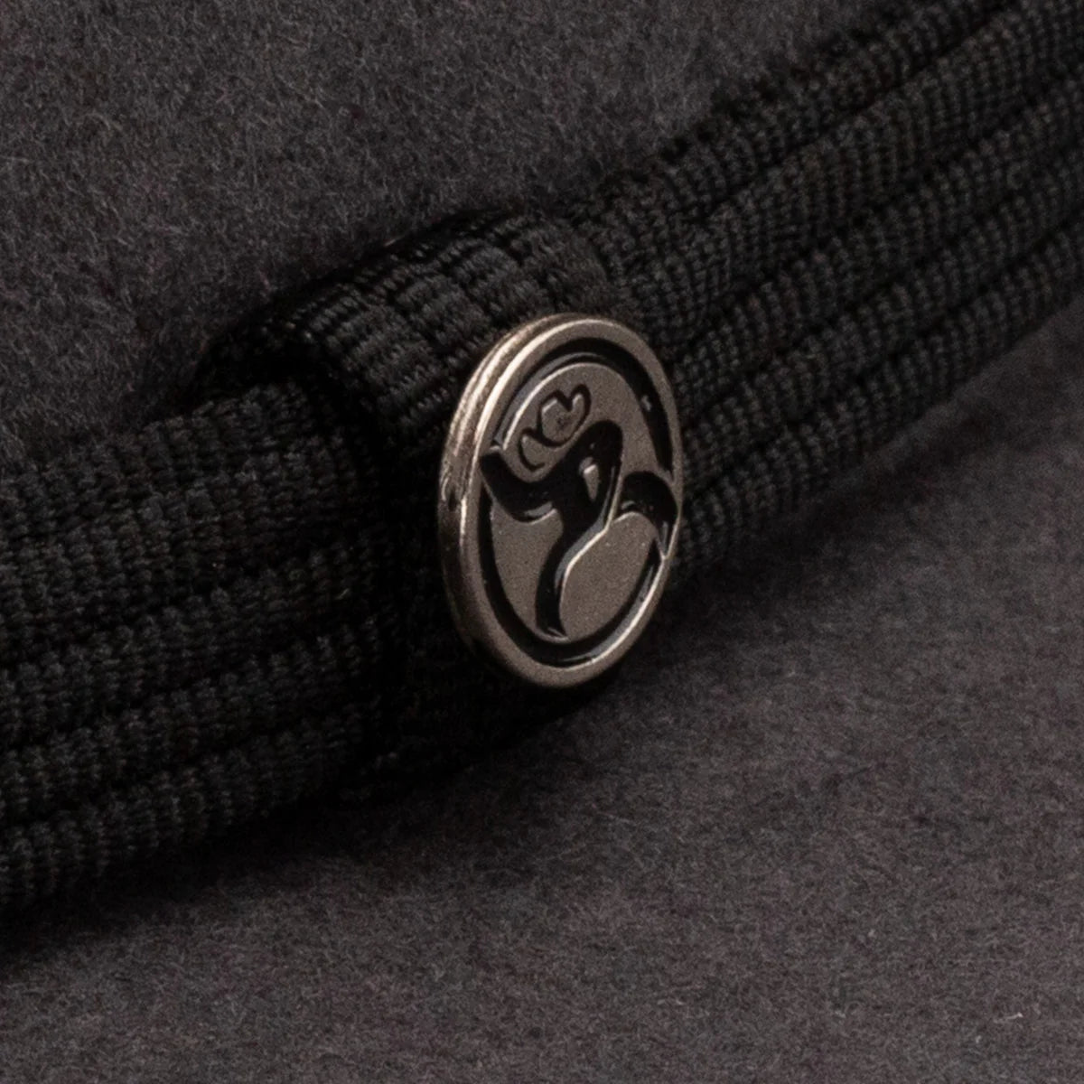 Resistol 4X Hooey Day Money Felt Cowboy Hat. Close-up of a black strap with a metallic logo on a dark background