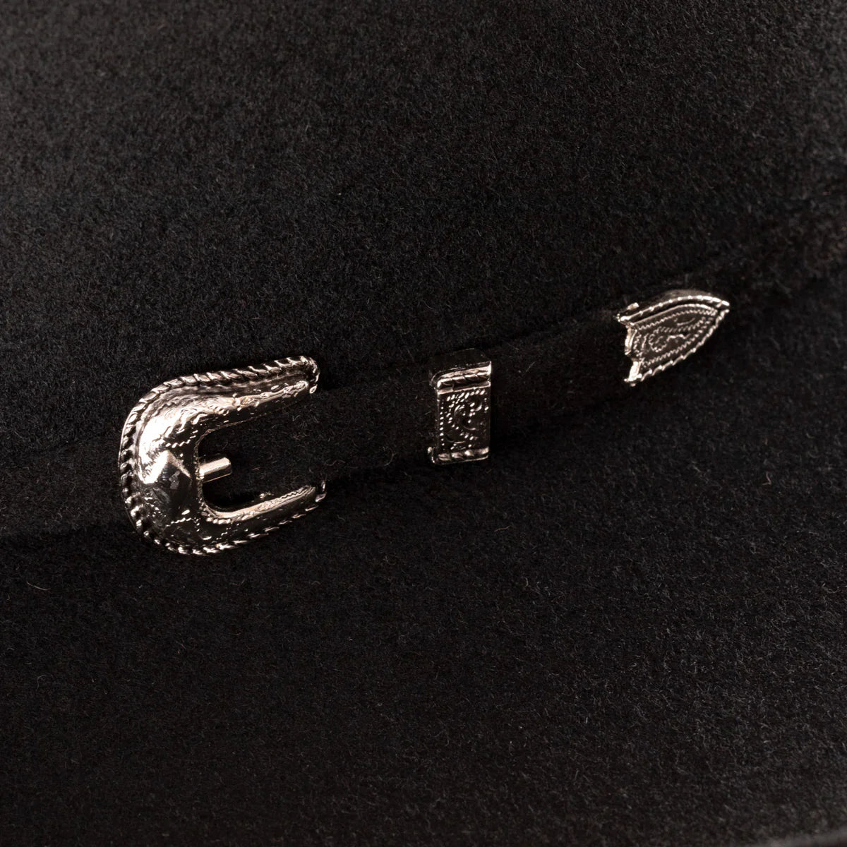 Resistol 3X Pay Window Felt Tuff Hedeman Cowboy Hat. Close-up of a black hat with decorative metal buckles on a dark background