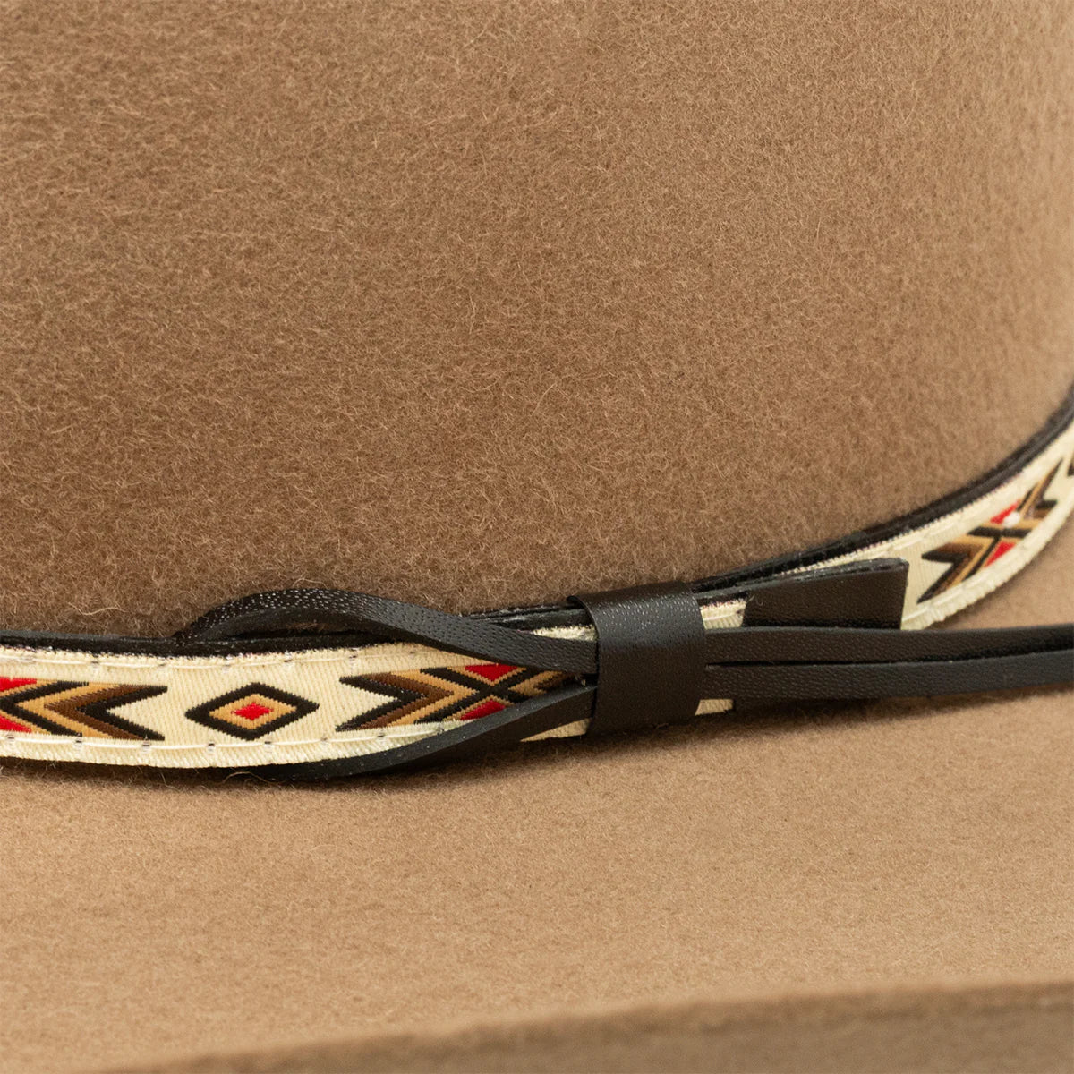Resistol 3X Tempe Tuff Hedeman Felt Cowboy Hat. Close-up of a brown cowboy hat with a decorative band featuring black, gold, and red patterns.