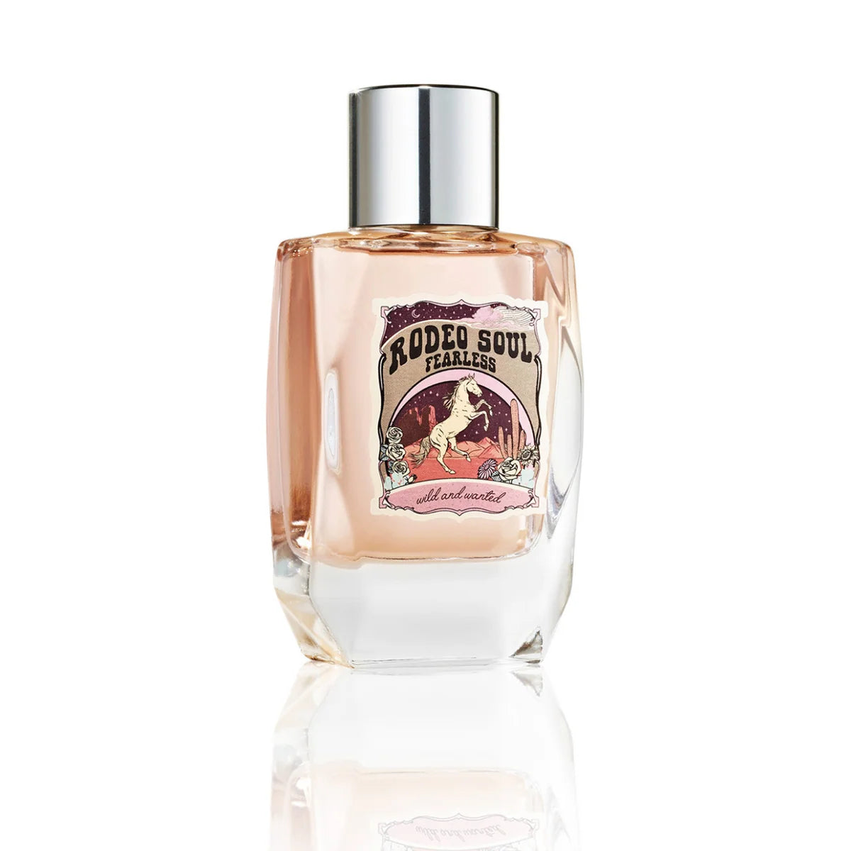 A bottle of Rodeo Soul Fearless cologne by All Over Me, featuring a clear glass bottle filled with pale pink liquid, a silver cap, and a vintage-style illustrated label, set against a clean white background with a soft reflection.