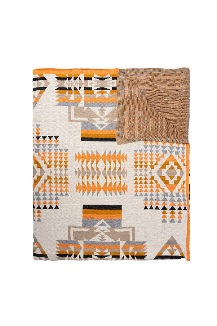 Talon Ridge Mesa Throw. A folded throw blanket with a geometric pattern featuring ivory and peach colors, along with tribal-inspired designs.