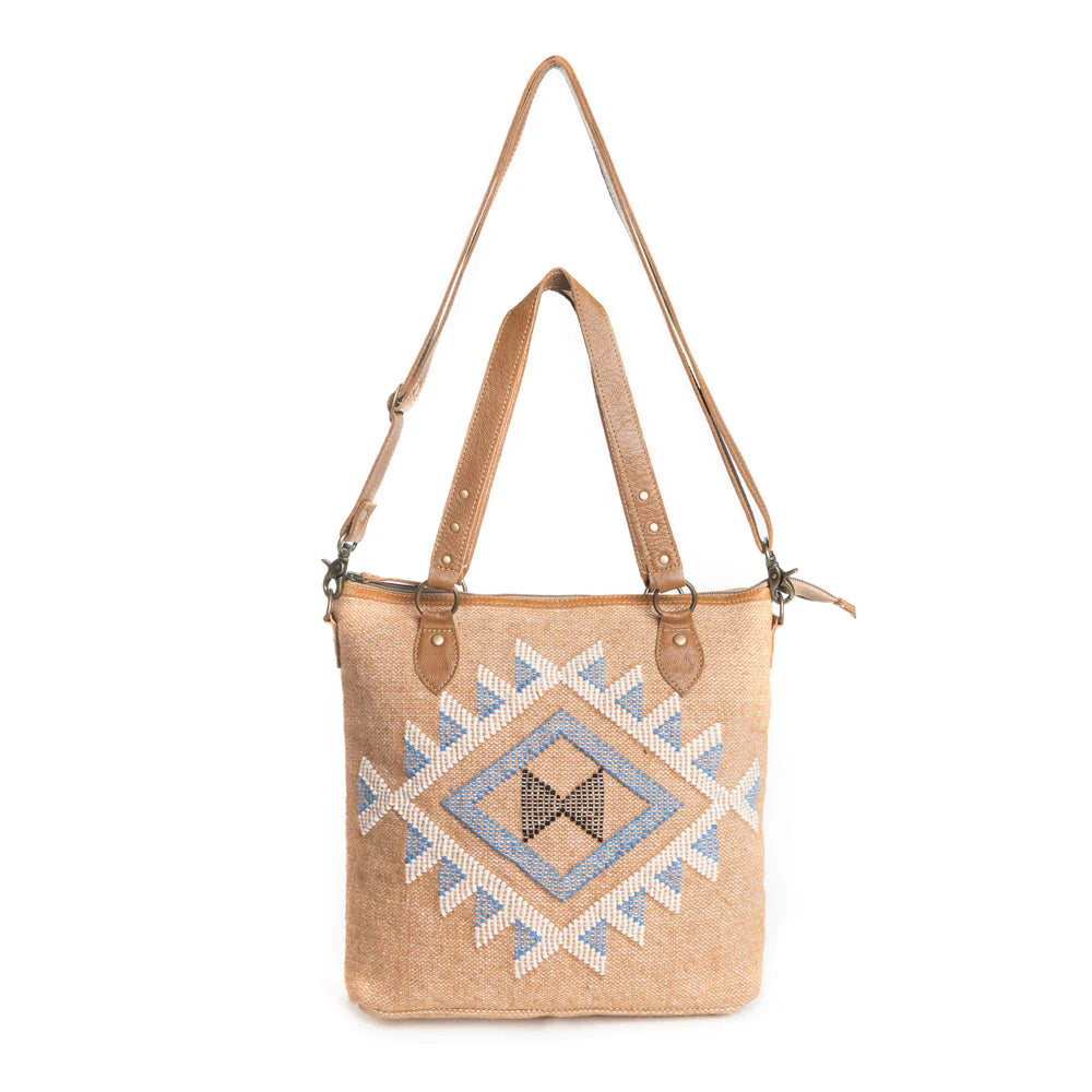 Prairie Magic Messenger BagA beige messenger bag with Southwestern geometric patterns in blue and white, featuring an adjustable shoulder strap and carrying handles. 