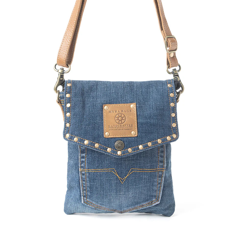 Denim crossbody bag with studded details and leather strap on a white background