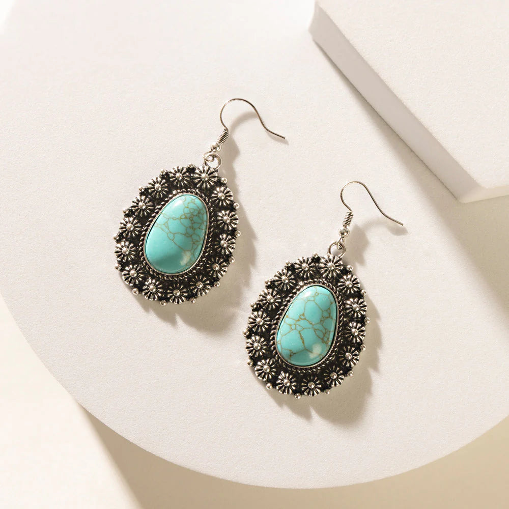 Turquoise earrings with decorative black frames on a white surface