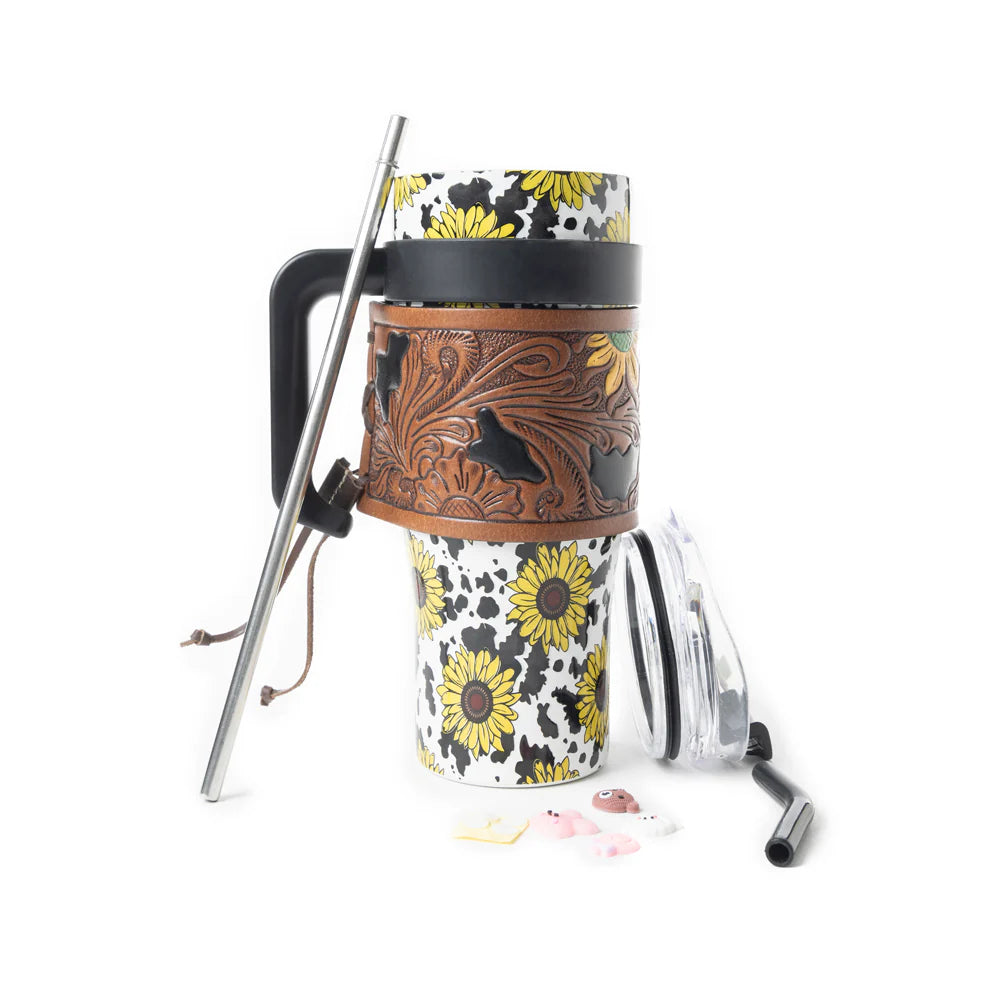 Wide Wyoming Tumbler In Yellow with Tooling. Tumbler with floral design and brown leather sleeve on a white background