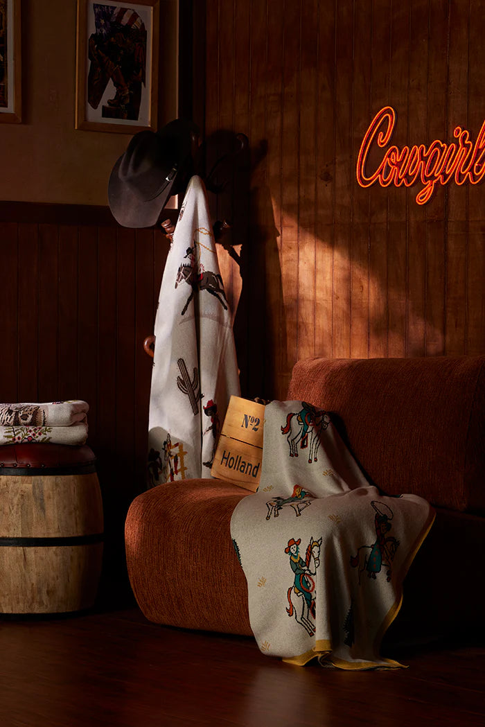 Neon sign 'Cowgirls' in a dimly lit room with cowboy hats and bandannas.