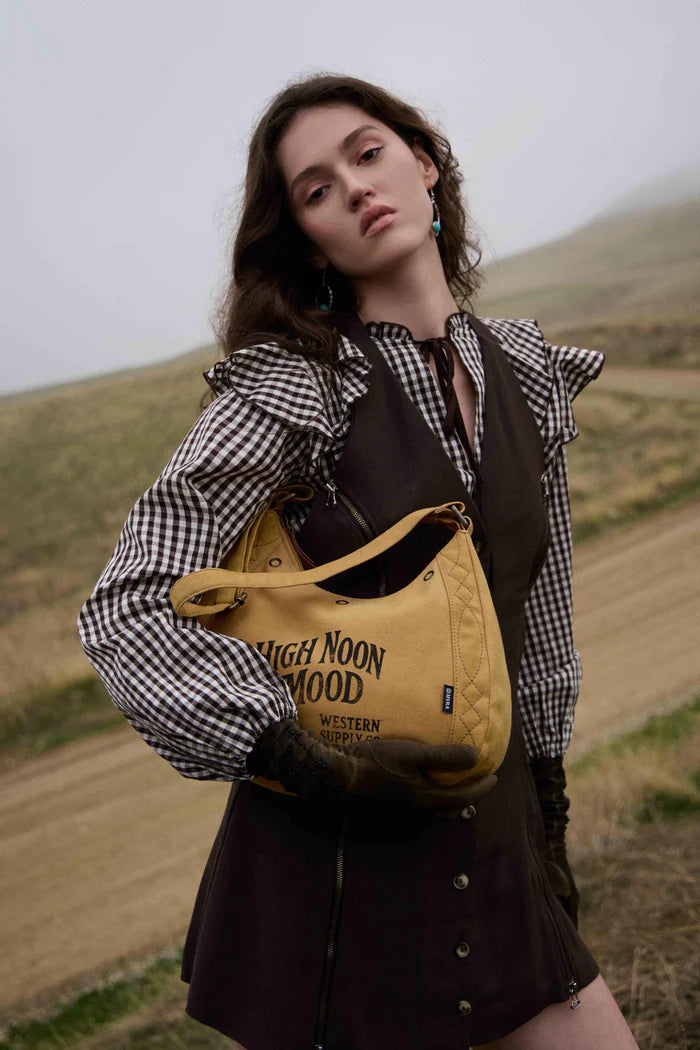 Woman holding a yellow bag with text in a field