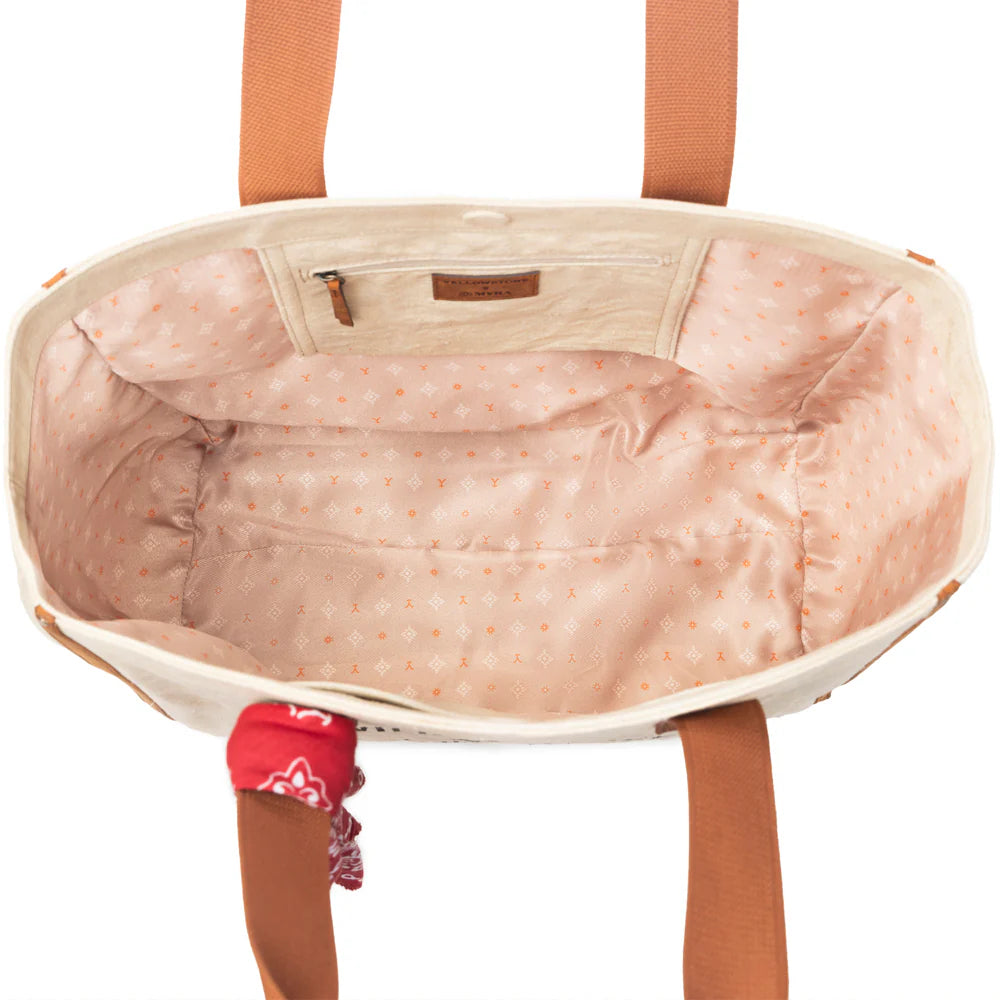 Yellowstone Ivory Creek Weekender Bag with Scarf. Beige tote bag with brown handles and a red bandana, featuring 'Yellowstone' branding.