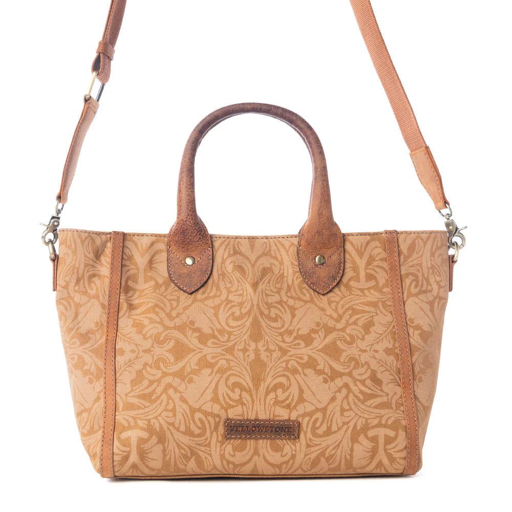 Yellowstone Wrangler’s Trail Crossbody with Pockets in Amber. Brown leather handbag with intricate patterns on a white background