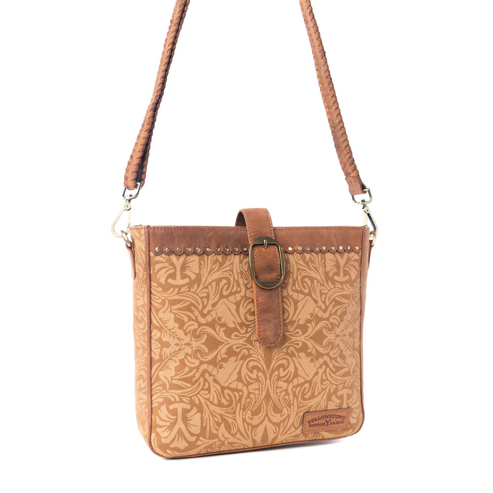Yellowstone Montana Amber Buckle Sling Bag. Brown leather crossbody bag with floral pattern on a white background