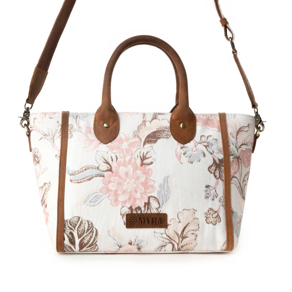 Floral-patterned handbag with brown handles and strap on a white background