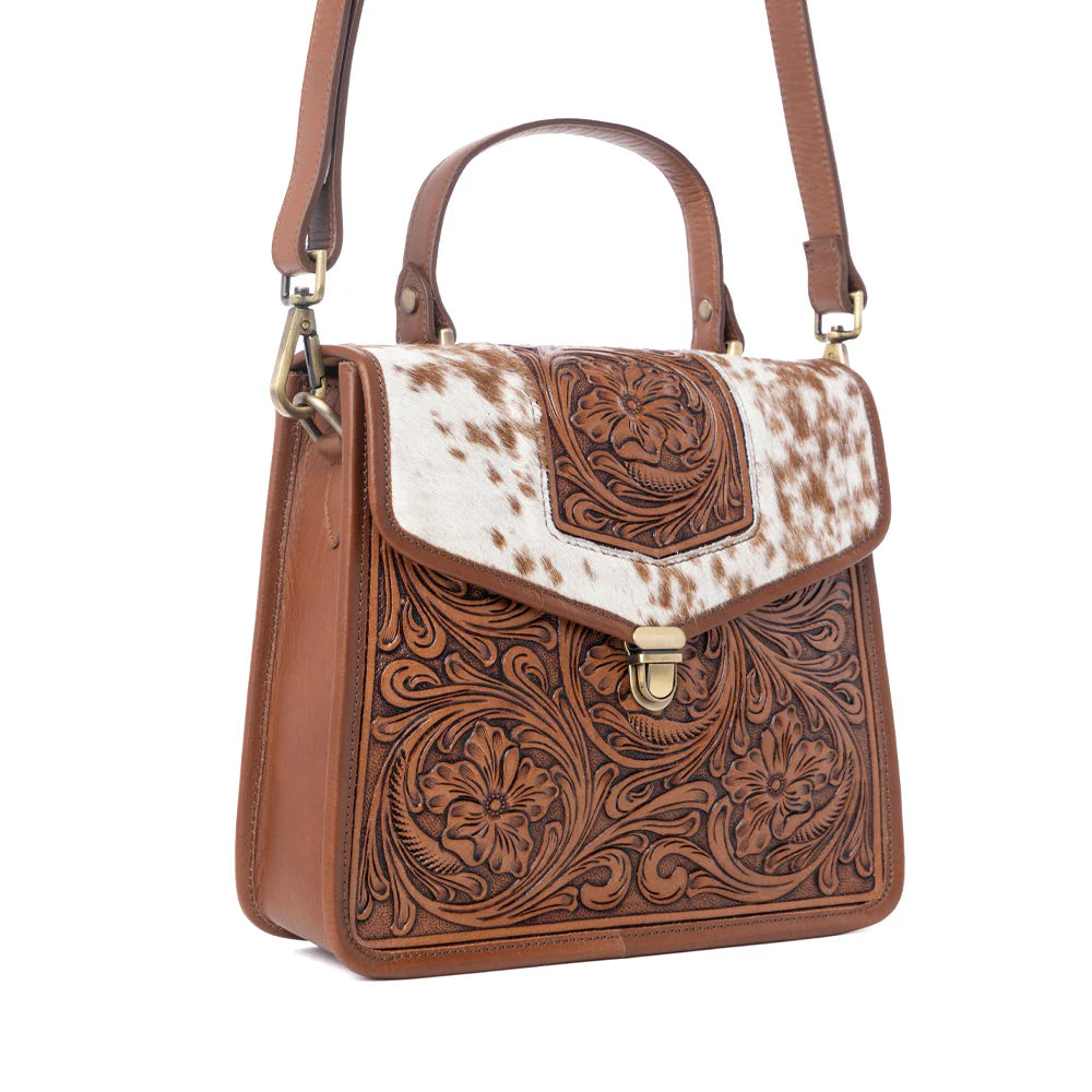 Brown leather handbag with white cowhide flap on a white background