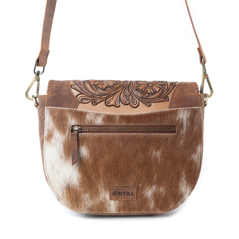 Brown and white cowhide leather bag with floral embossing on a white background
