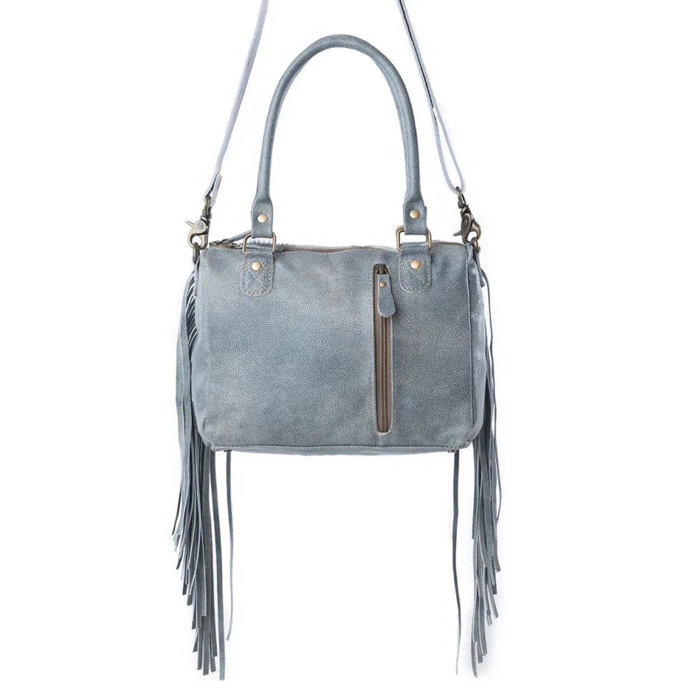 Gray suede handbag with fringe details on a white background