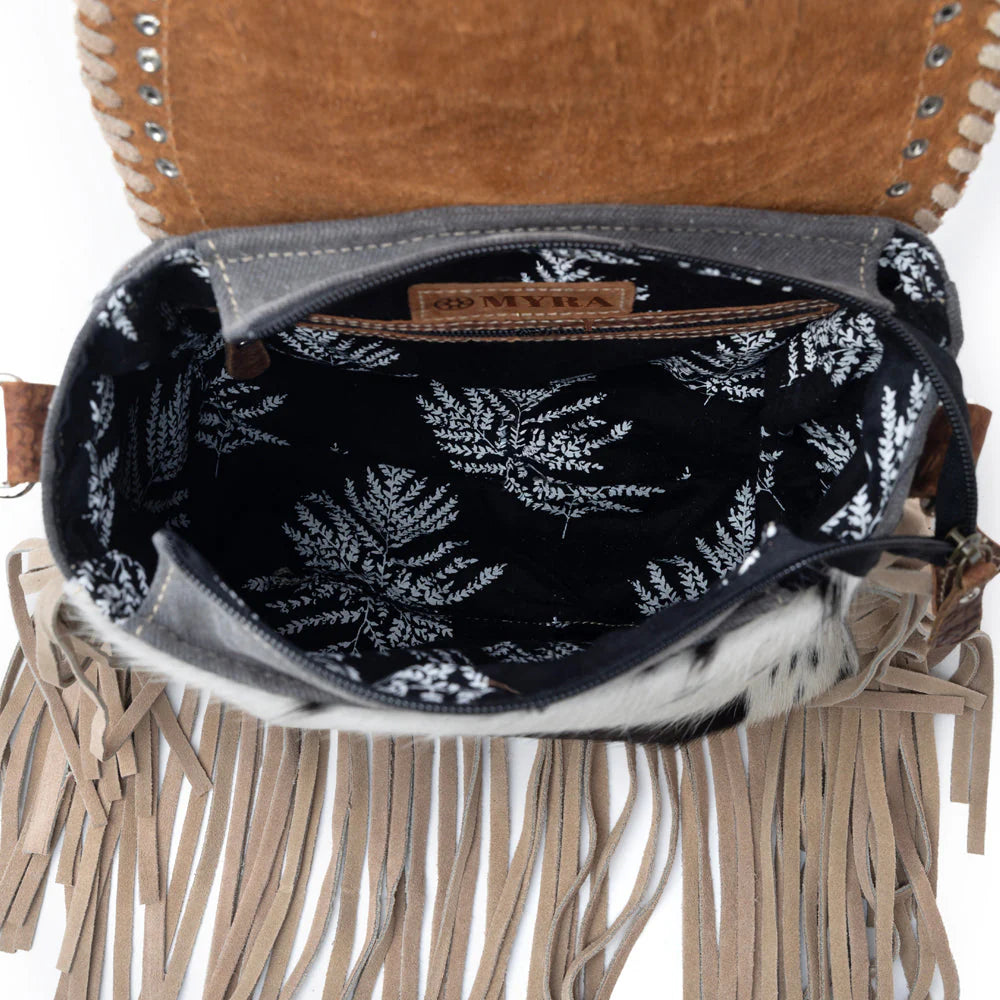 Close-up of a brown leather bag with fringe details and a black floral patterned interior.