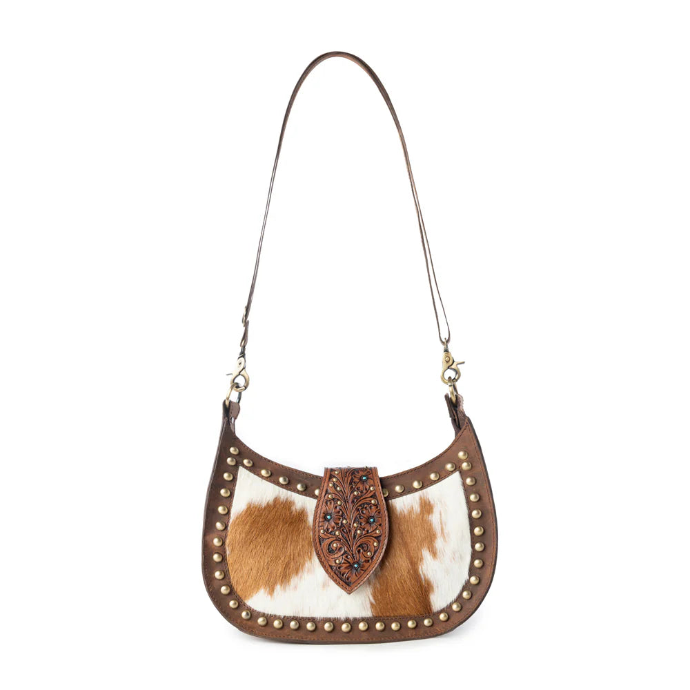 Brown and white cowhide handbag with decorative studs on a white background