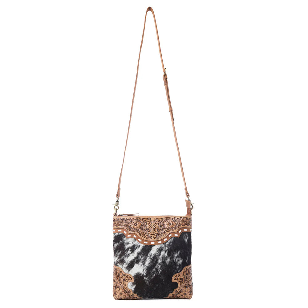 Handbag with cowhide pattern and decorative strap on a white background