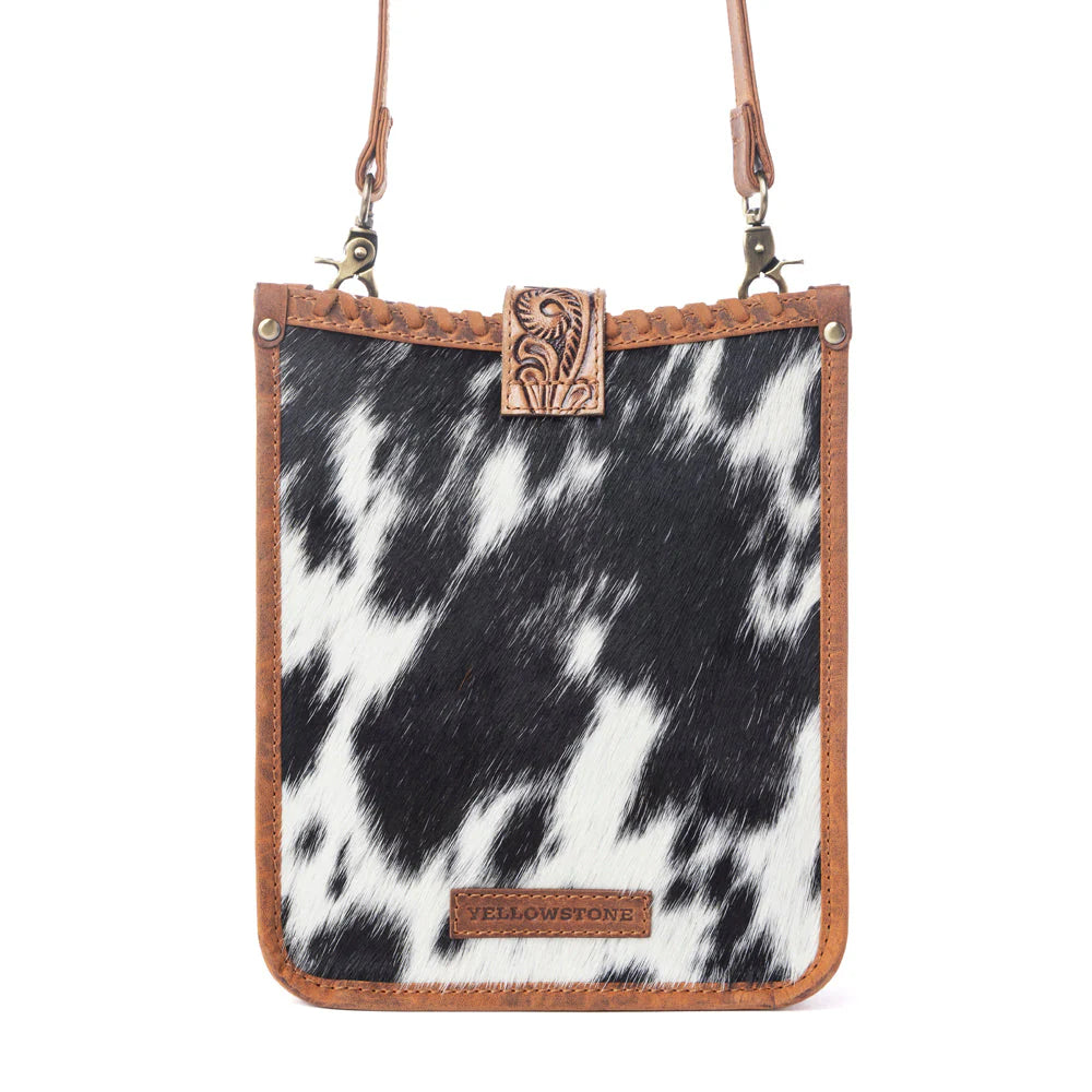 Phone case with black and white cowhide pattern and brown leather accents on a white background