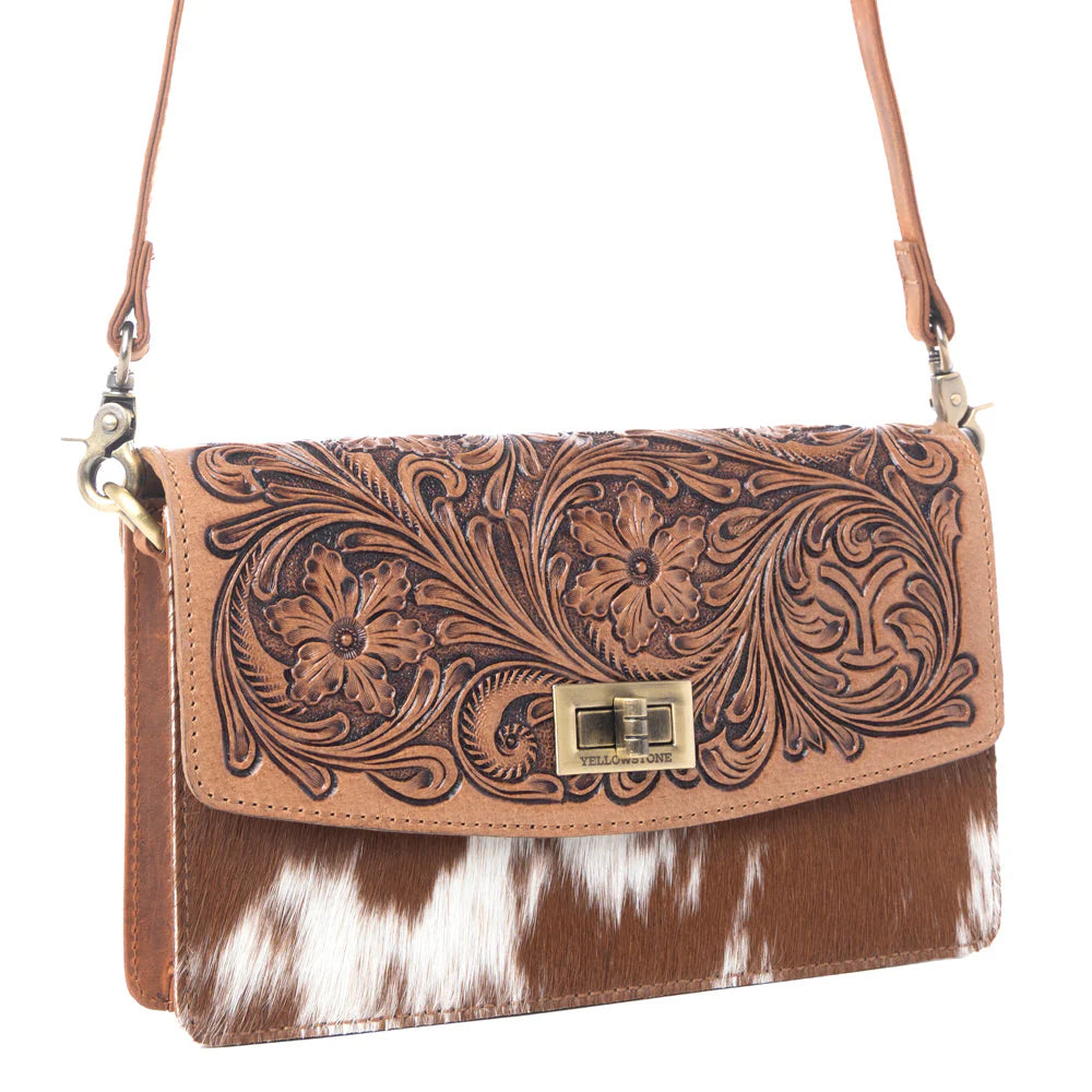 Brown leather handbag with floral patterns and cowhide texture on a white background