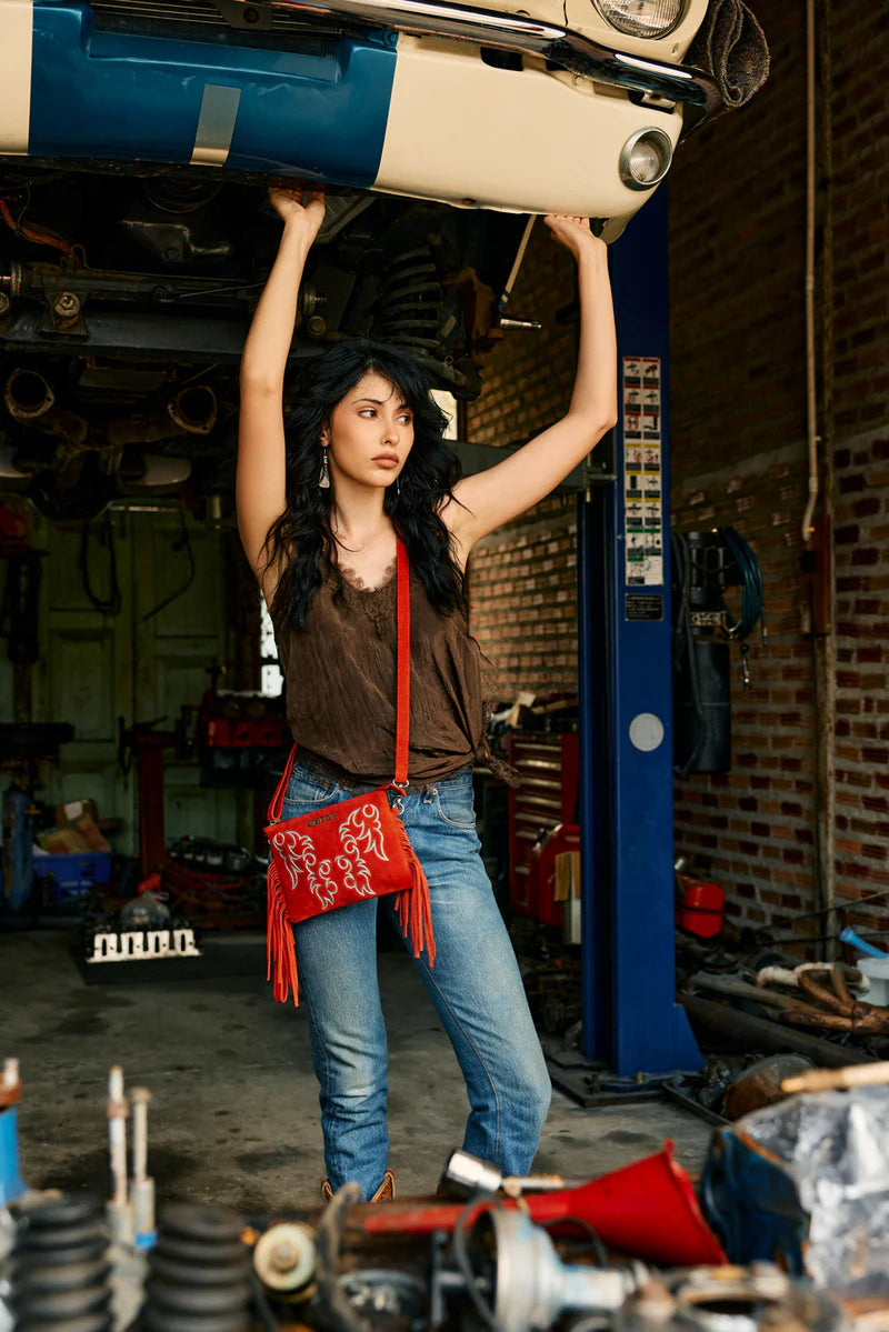Woman holding a car part above her head in a garage.