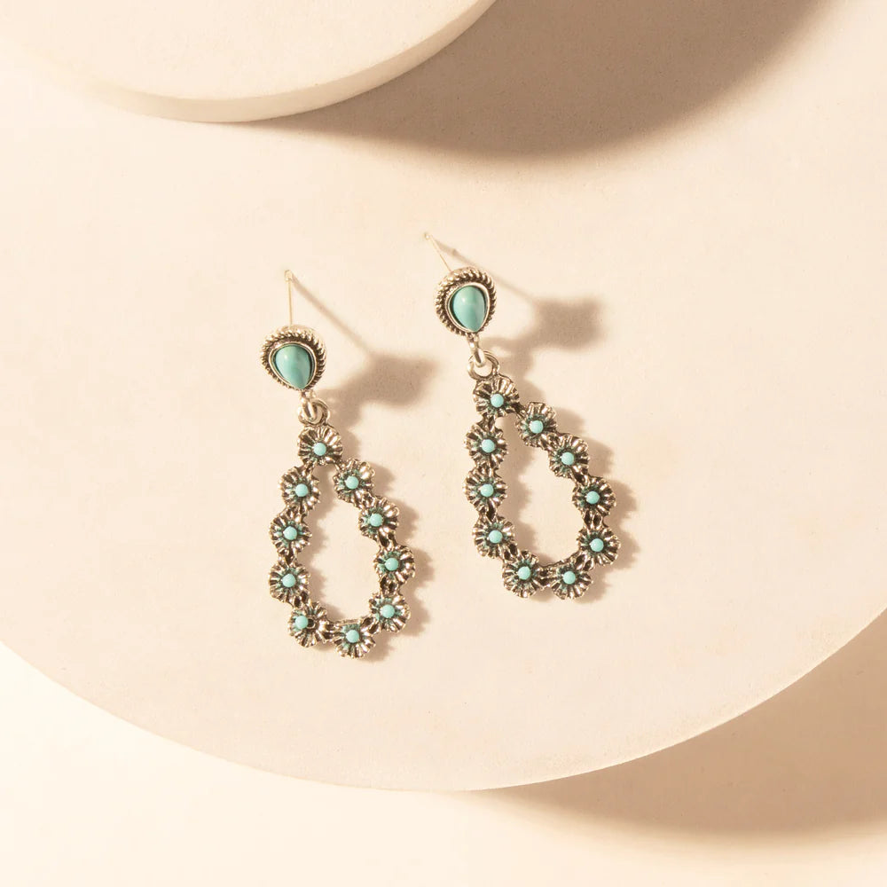 Pair of earrings with turquoise stones on a beige background
