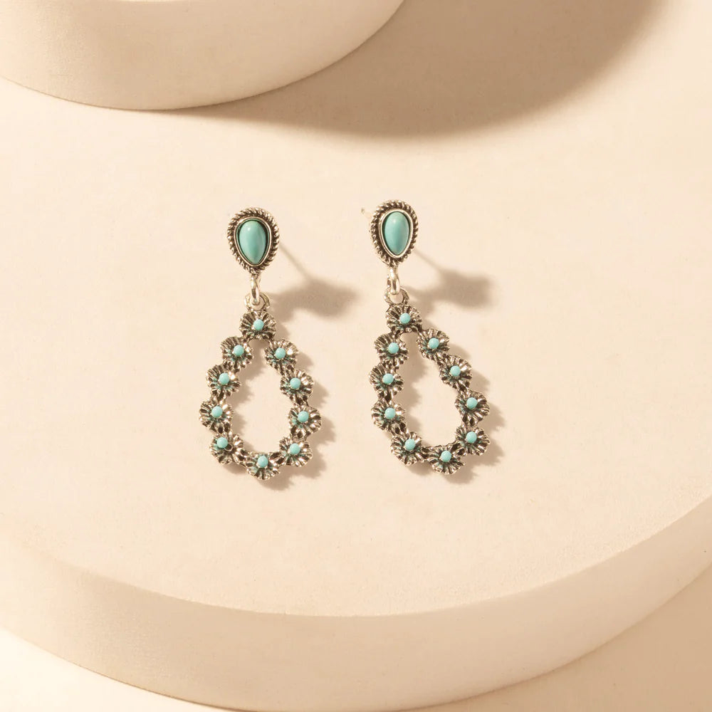 Pair of earrings with turquoise stones on a beige background