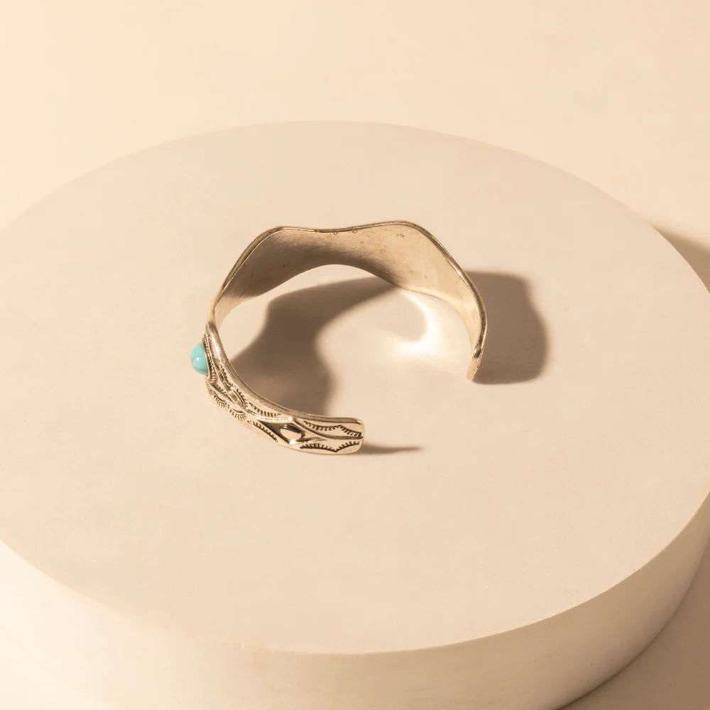 Gold ring with a turquoise stone on a beige background