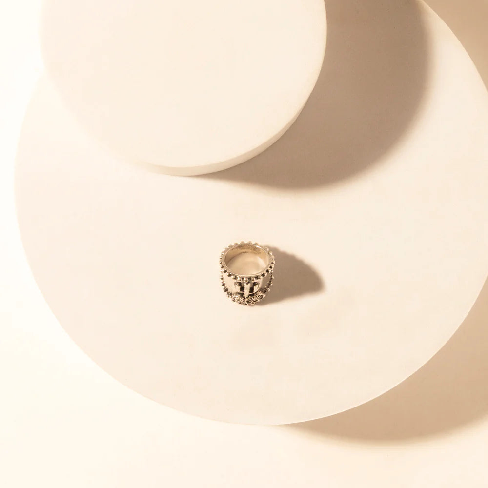 Silver ring on a beige ceramic plate with soft shadows