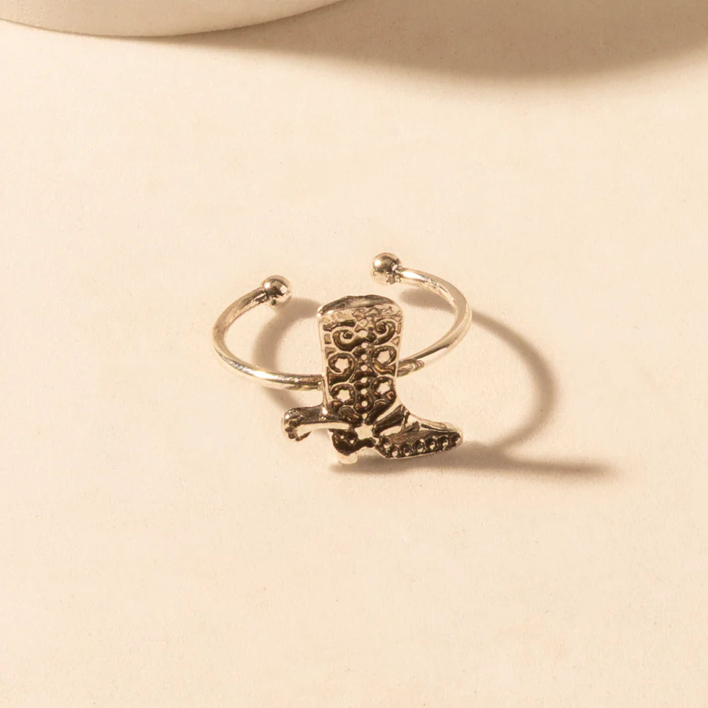 Silver boot-shaped ring on a beige background