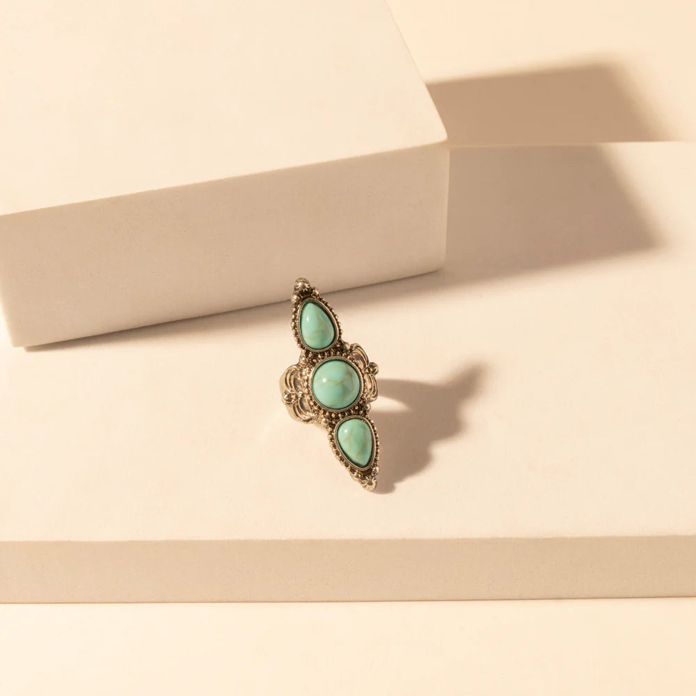 Ring with turquoise stones on a beige surface