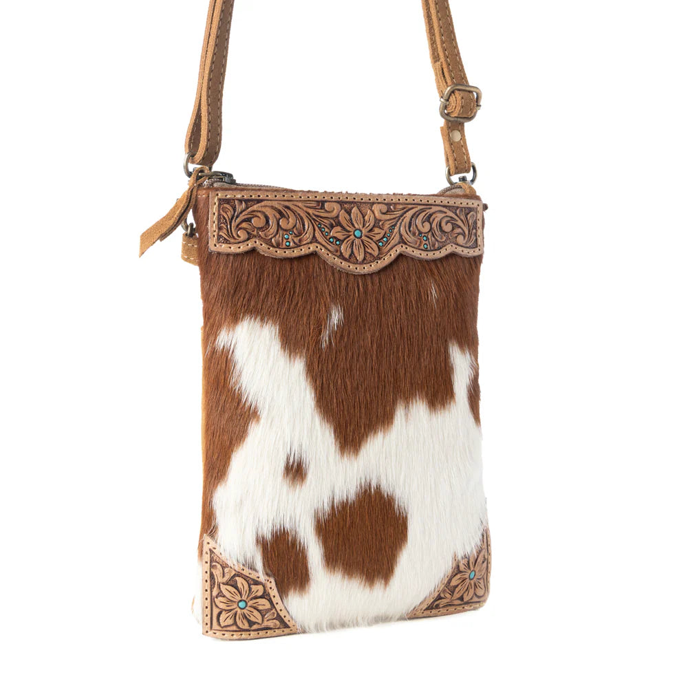 Cowhide crossbody bag with decorative leather trim on a white background