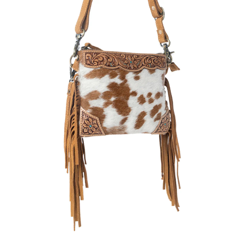 Brown and white cowhide leather crossbody bag with fringe on a white background
