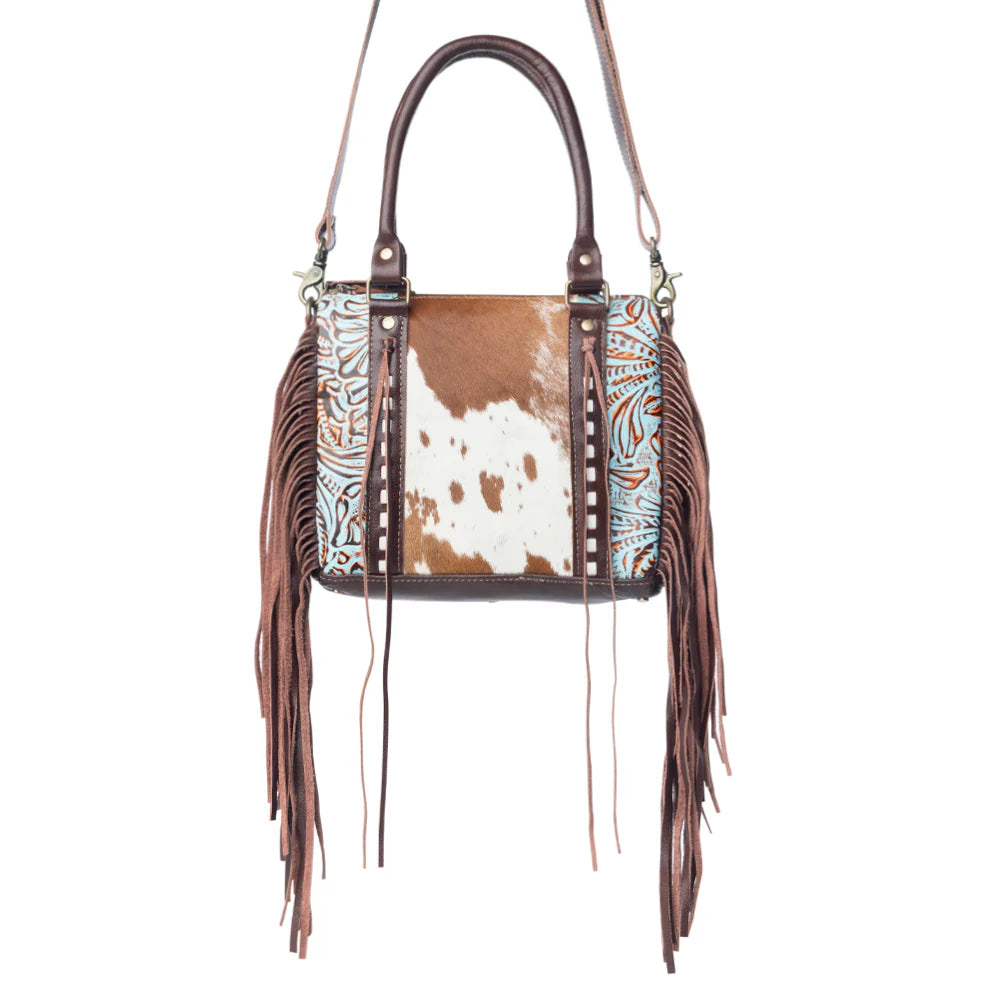 Handbag with cowhide pattern and fringe details on a white background
