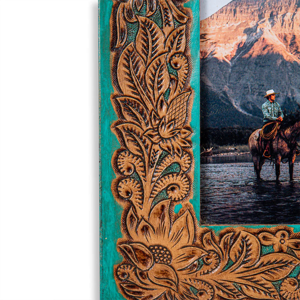 Time of Traditions Hand-Tooled Photo Frame. A hand-tooled leather photo frame with a turquoise teal background and brown detailed scrolling design, holding a picture of a person on horseback.