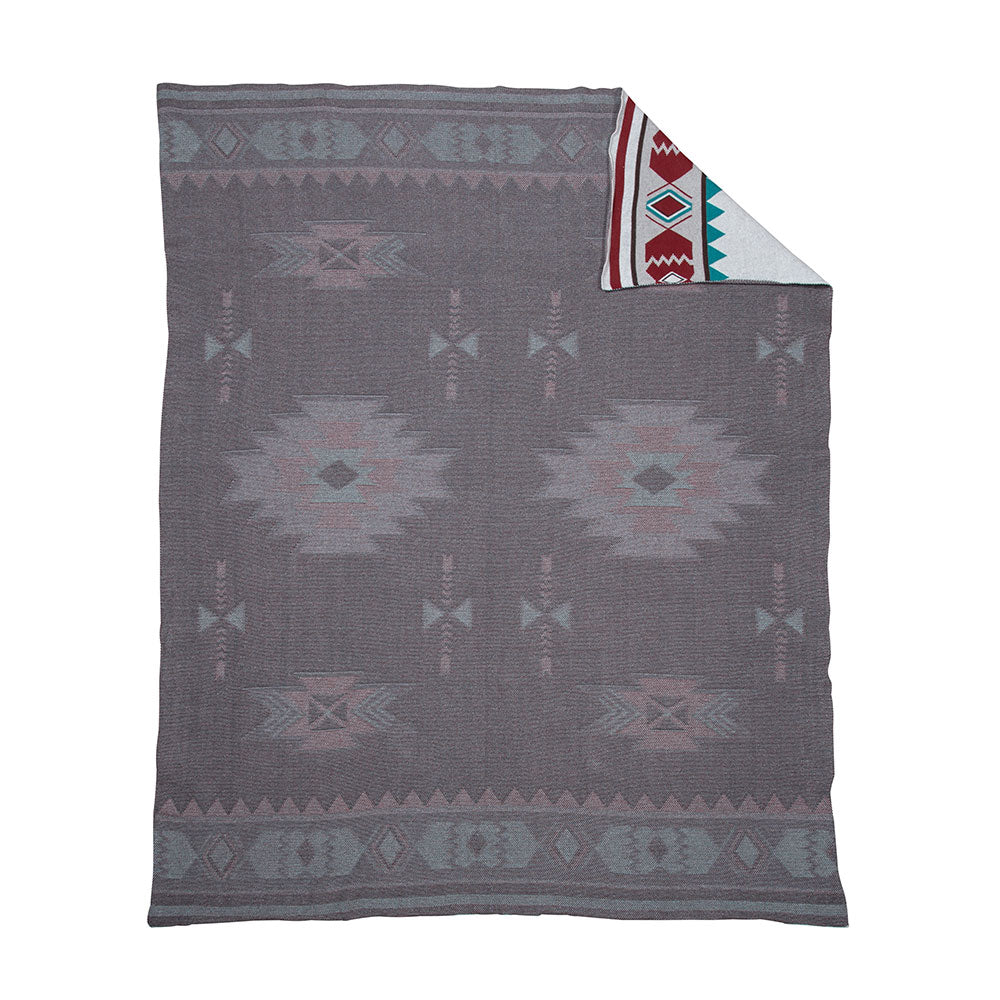Canyon View Woven Throw. A throw blanket with geometric patterns primarily in gray, with accents of red and white, unfolded on a flat surface.