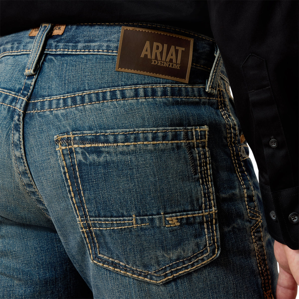 Ariat Men's M5 Boundary Straight Leg Jean. Close-up of blue jeans with Ariat denim label on the back pocket.