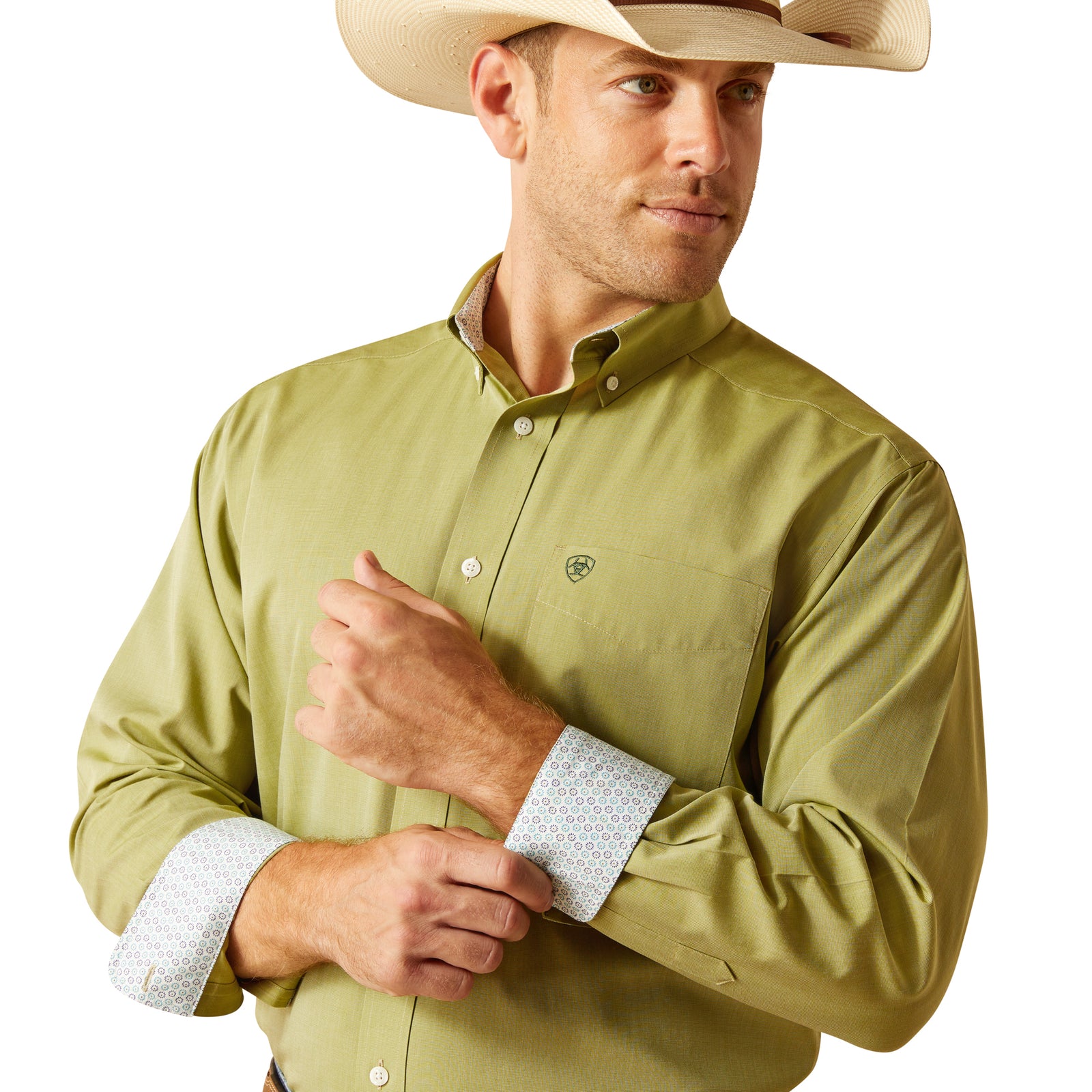Ariat Men's Wrinkle Free Solid Pinpoint L/S Western Shirt. A man wearing a green long-sleeved Ariat Western shirt with a contrast collar, button-up shirt with wrinkle-free finish, standing next to a pair of blue jeans.