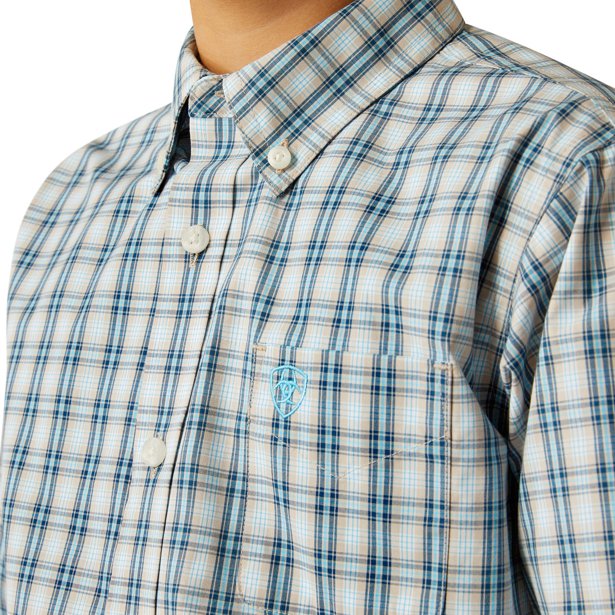 Ariat Boy's Pro Series Shelton L/S Western Shirt. Close-up of a blue and white plaid shirt with a logo on a white background