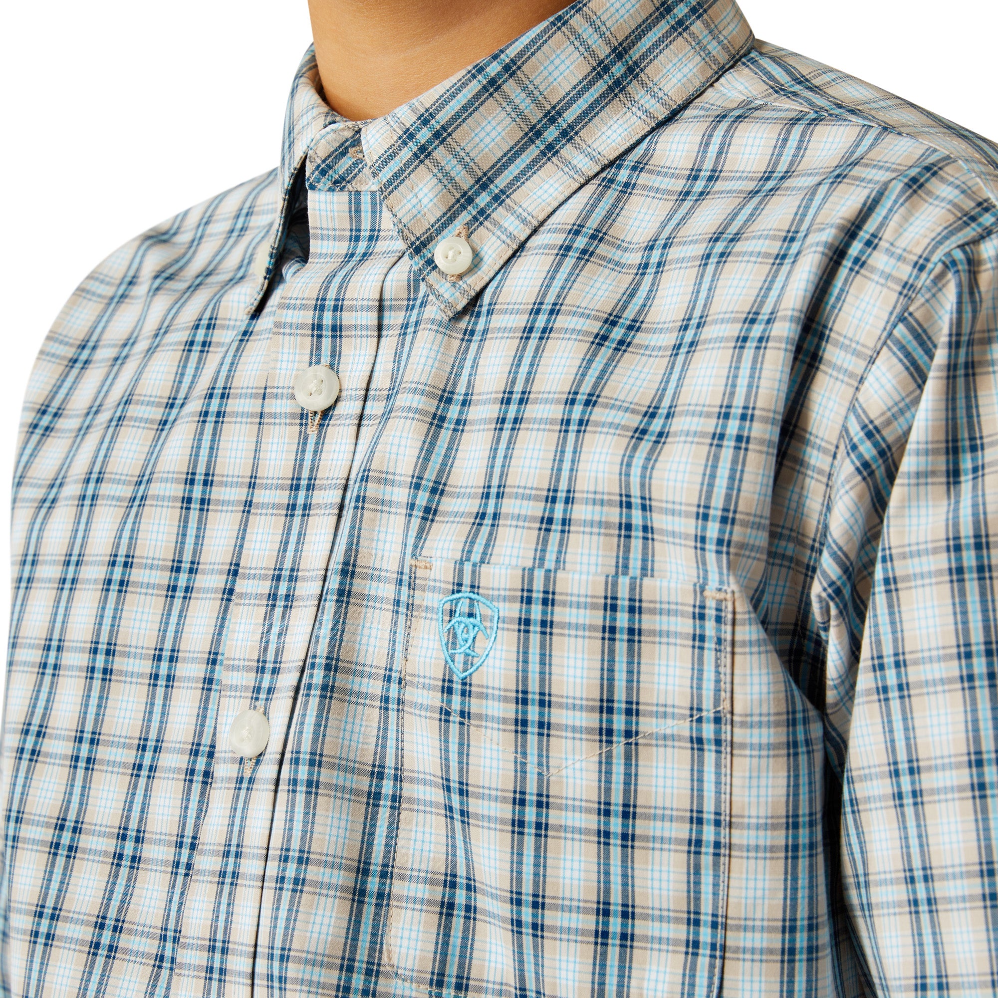 Ariat Boy's Pro Series Shelton L/S Western Shirt. Close-up of a blue and white plaid shirt with a logo on a white background