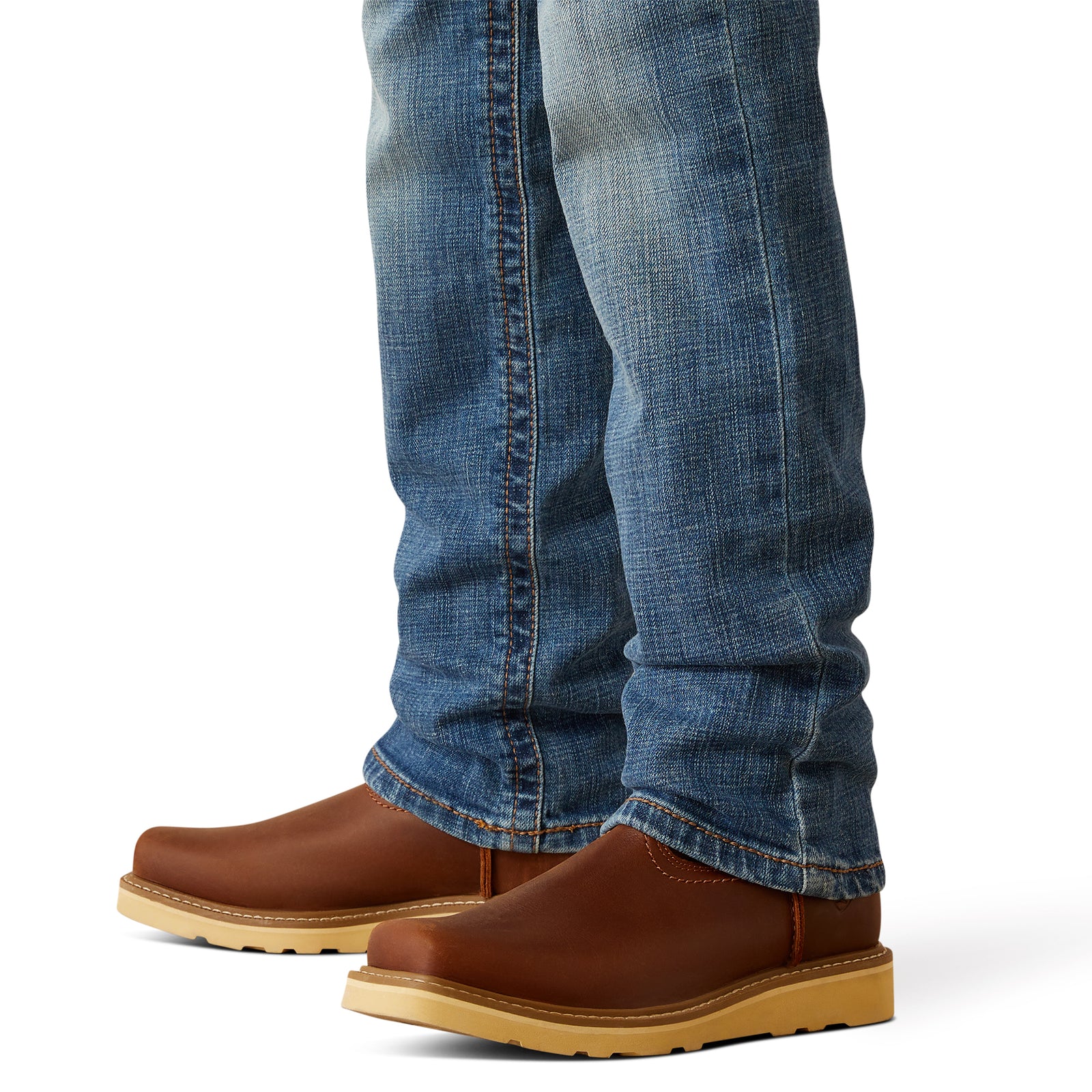 Ariat Boy's B5 Norwich Slim Fit Jean. Brown leather shoes worn with blue jeans on a white background