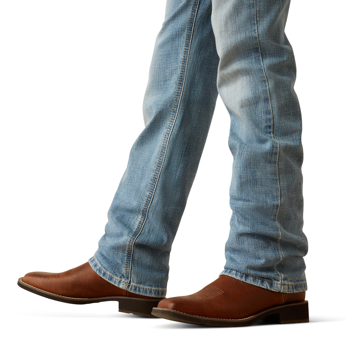 Ariat Boy's B4 Relaxed Jones Boot Cut Jeans. Close-up of blue jeans and brown boots on a white background