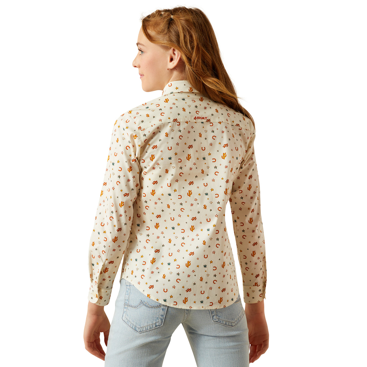 Ariat Girl's Team Kirby L/S Western Shirt. Woman wearing a patterned shirt and light blue jeans on a white background