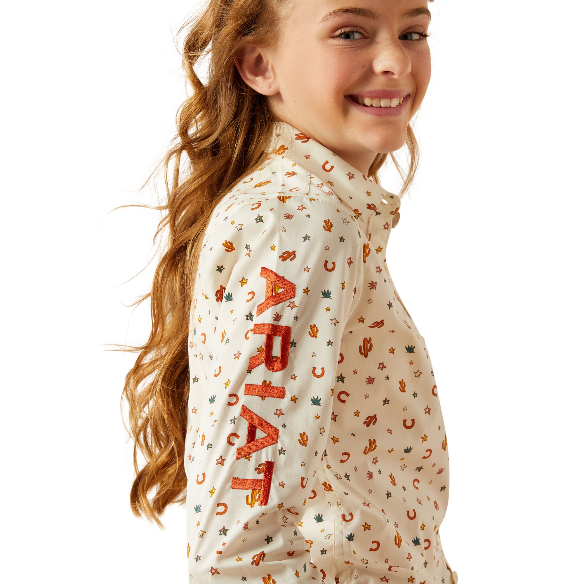 Ariat Girl's Team Kirby L/S Western Shirt. Girl wearing a patterned shirt with visible branding on a white background