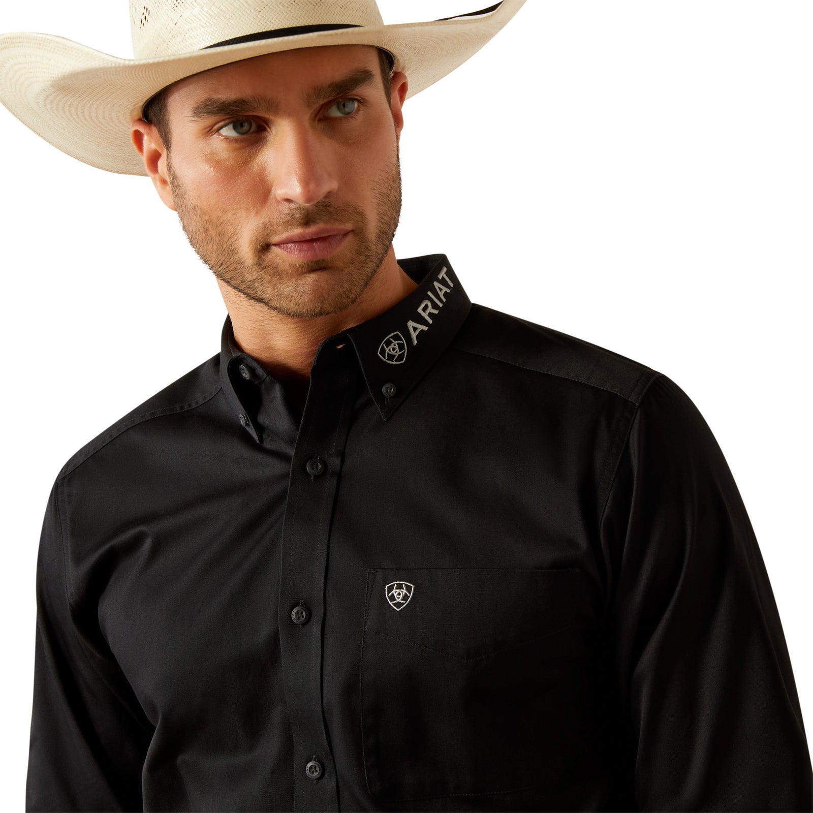 Ariat Men's Team Logo Twill L/S Western Shirt. Man wearing a black Ariat shirt and cowboy hat on a white background